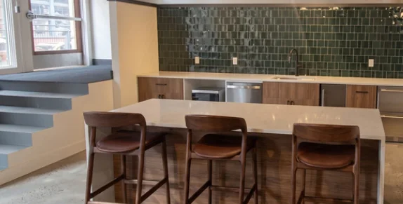 The coffee bar: a long counter with leather stools in front of a green tiled wall