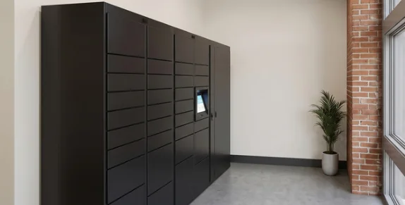A bank of black smart package lockers beside an exposed brick column