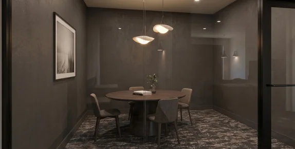A study room with a round table, pendant lights and dark walls behind a glass door